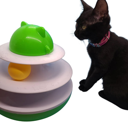 Albert Catstein turntable cat toy with green top, white tiers, and a yellow ball. A black cat watches the toy.